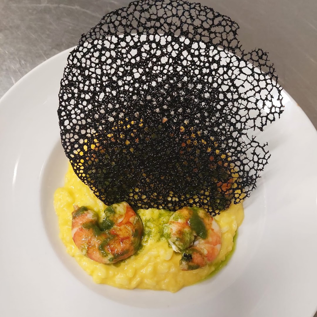 Un risotto aux crevettes avec une fine tuile noire